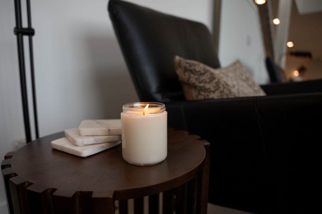 A flickering soy candle in a cozy home setting, paired with a blanket, a warm drink, and a TV remote for the perfect binge-watching night.