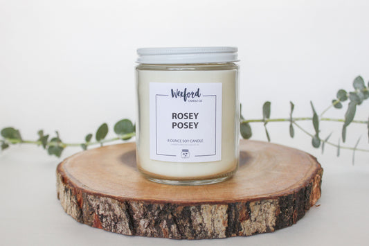 Rosey Posey soy candle by Wexford Candle Co., a floral-scented candle with notes of berry, pear, rose, jasmine, and sandalwood. A limited-edition spring favorite in a cozy home setting.